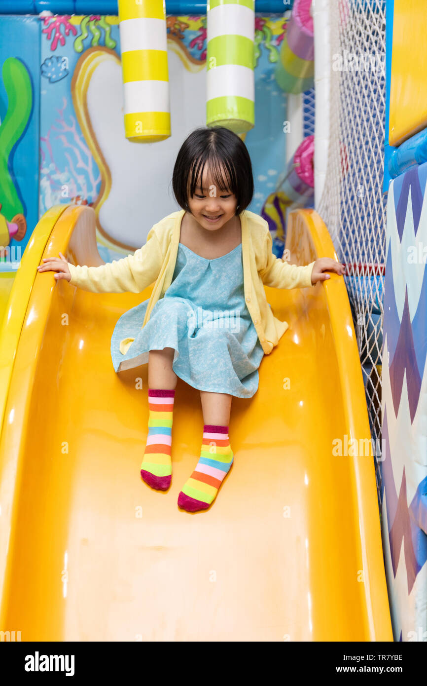Asian Chinese little girl playing on the slide at indoor playground ...