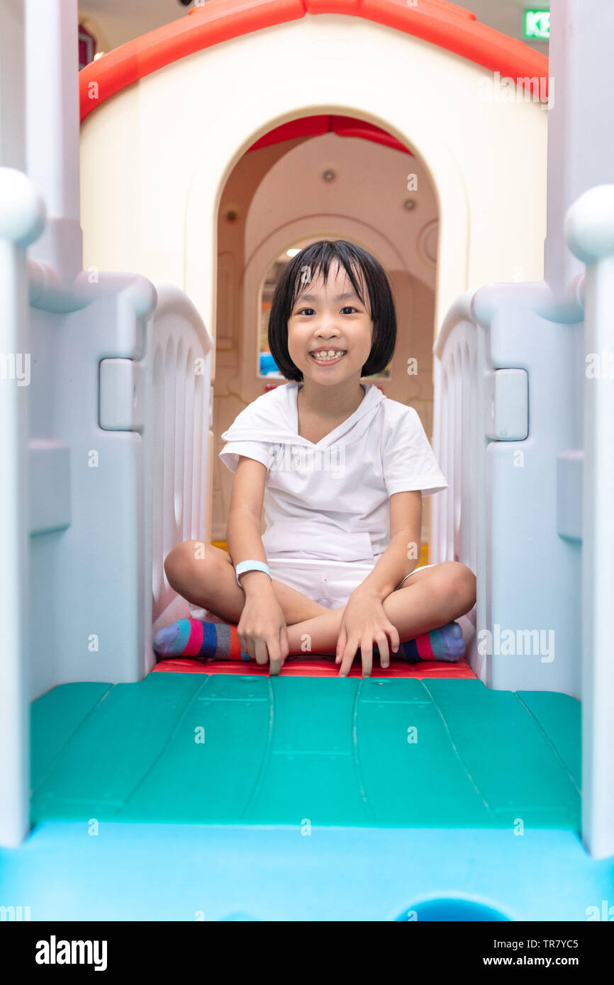 Asian Chinese little girl playing in toy house at indoor playground ...