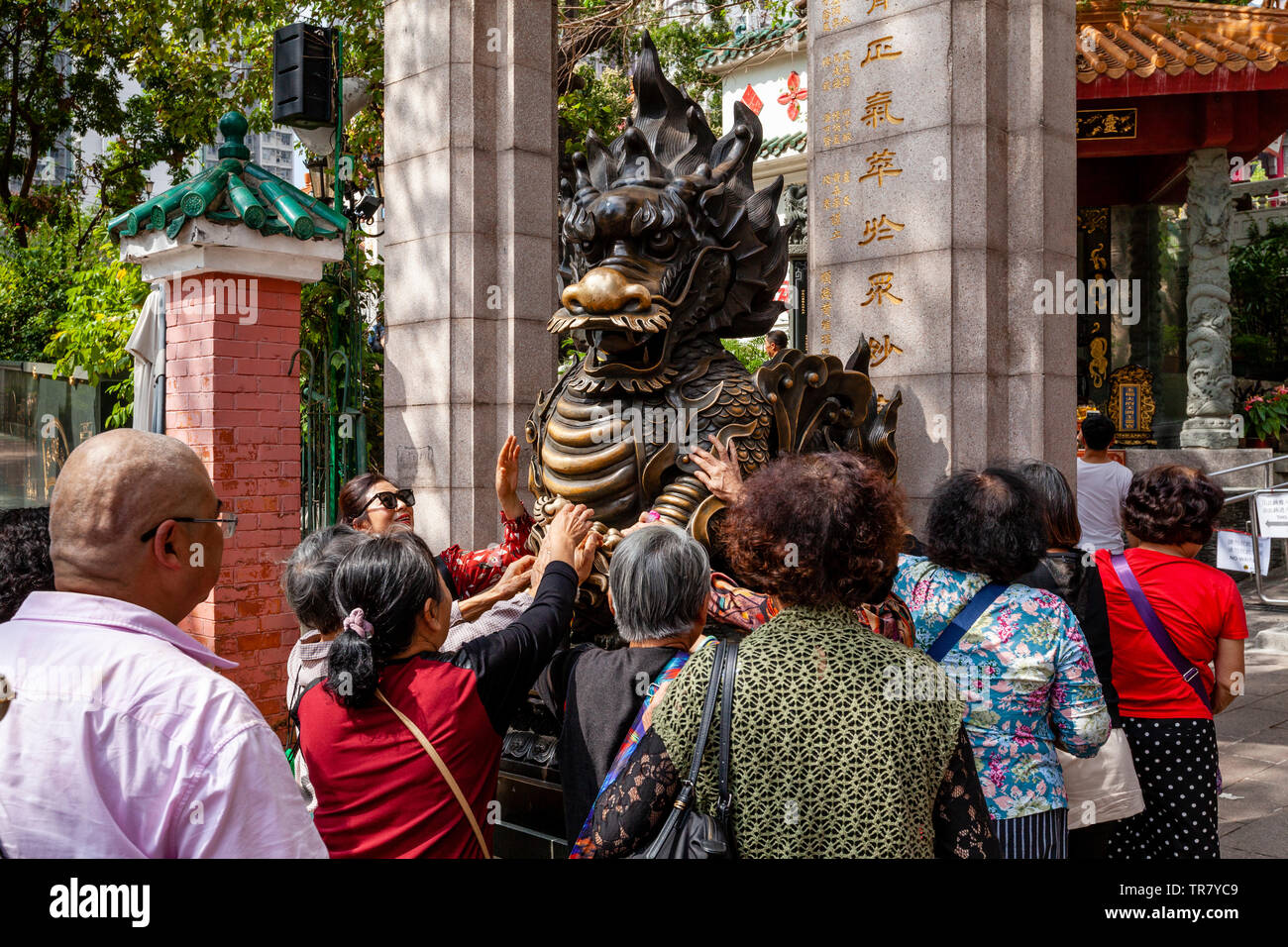 Chinese Tourists Rub The Dragon Statue For Good Luck At The Entrance To