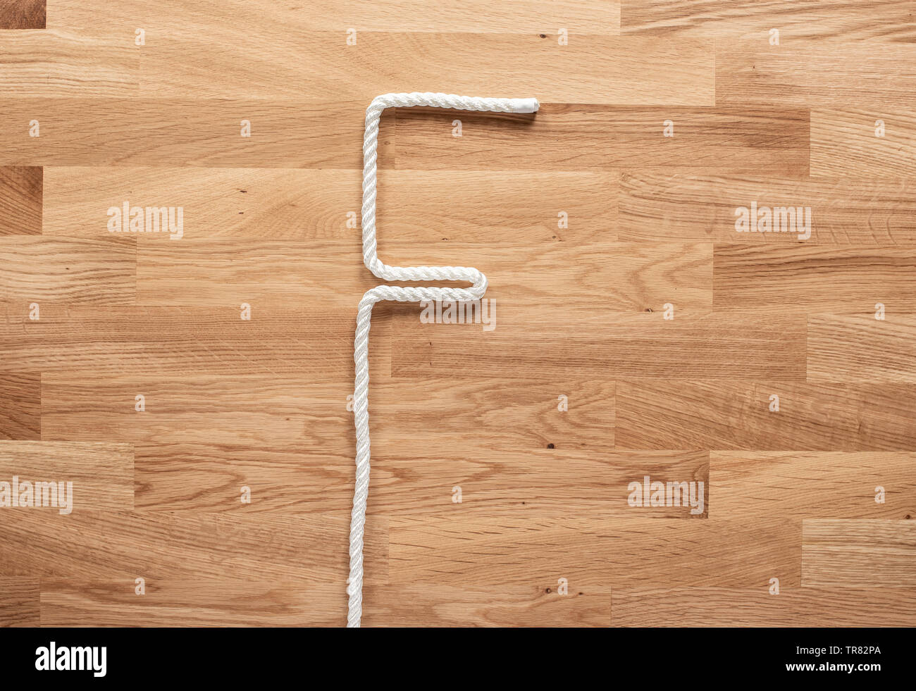 The letter F formed with white rope on a wooden table Stock Photo