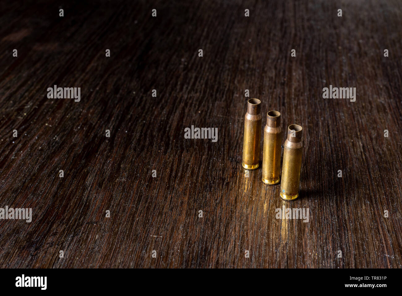 Empty bullet casings on a dark, wooden table. Stock Photo