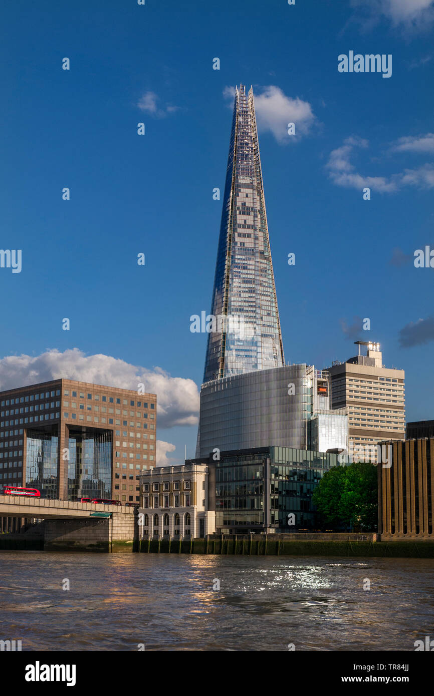 The London Shard with One London Bridge, red bus and riverside city offices. River Thames in foreground viewed from commuter RB1 river boat London UK Stock Photo