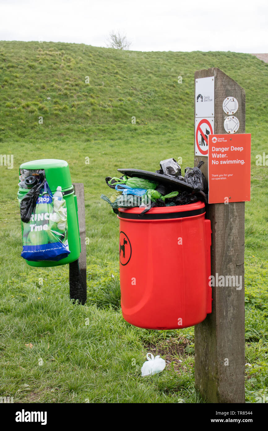 Overflowing litter bin and dog waste bin in the countryside, England UK Stock Photo