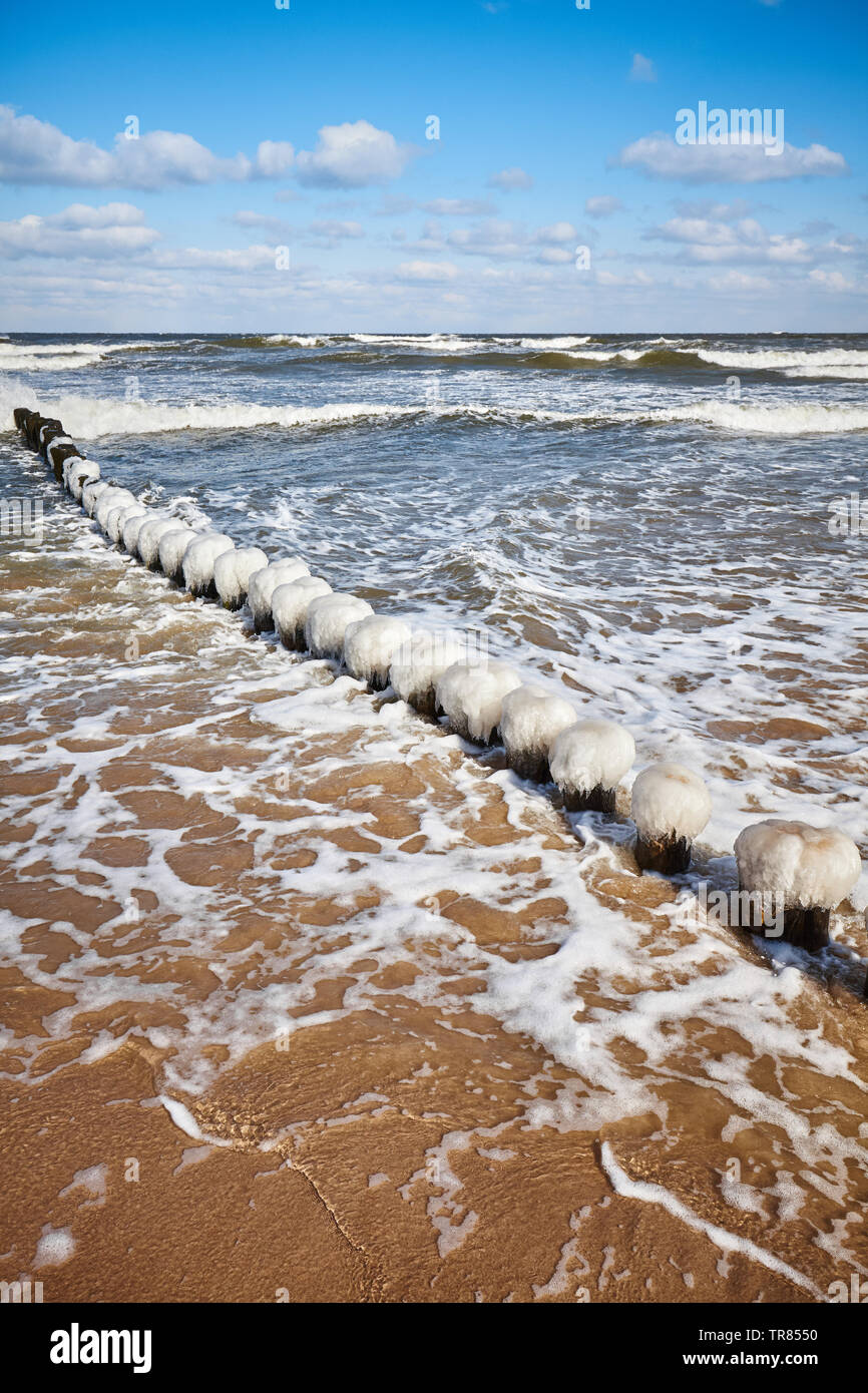 Beach with an icy breakwater on a sunny winter day. Stock Photo