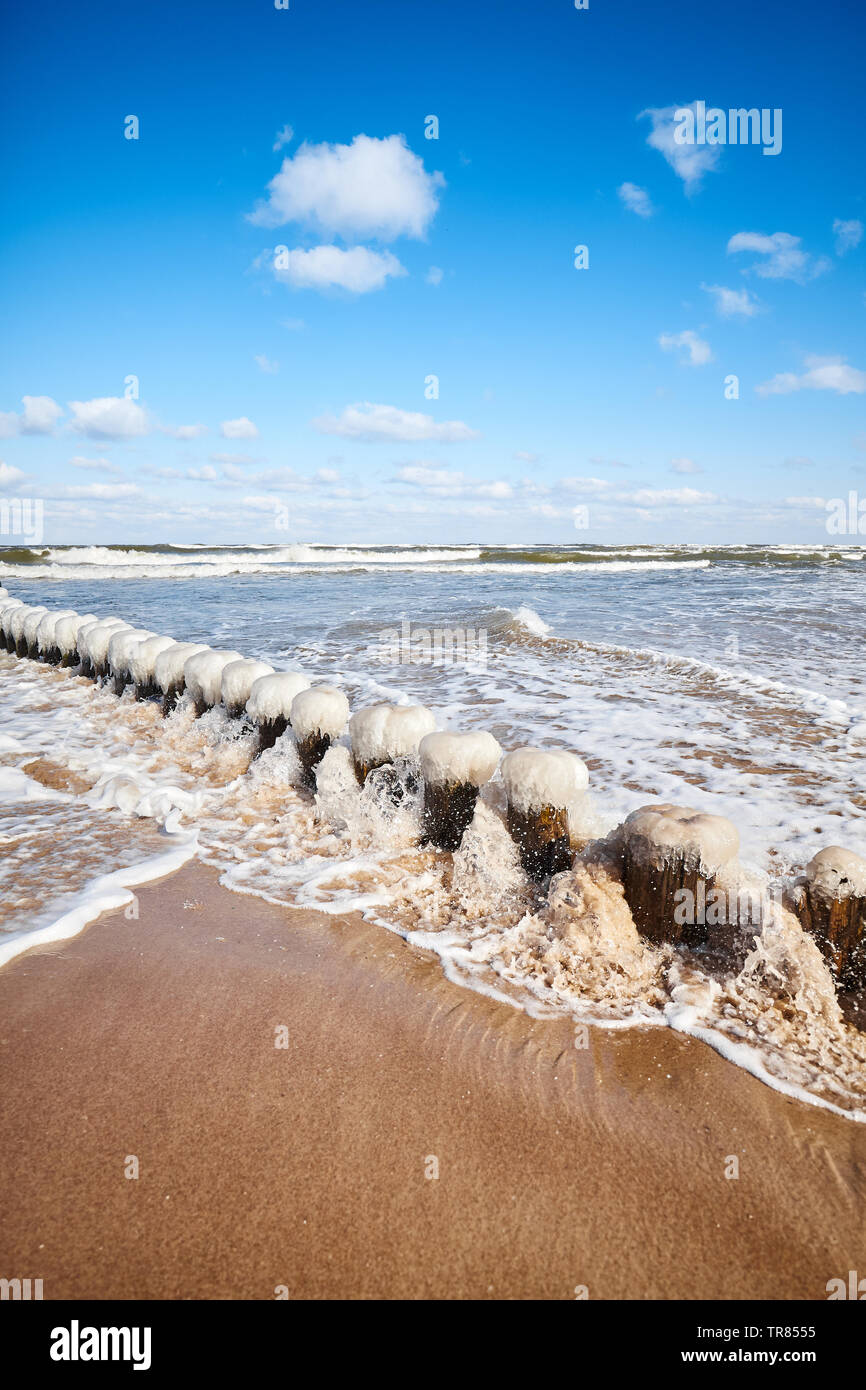 Beach with an icy breakwater on a sunny winter day. Stock Photo