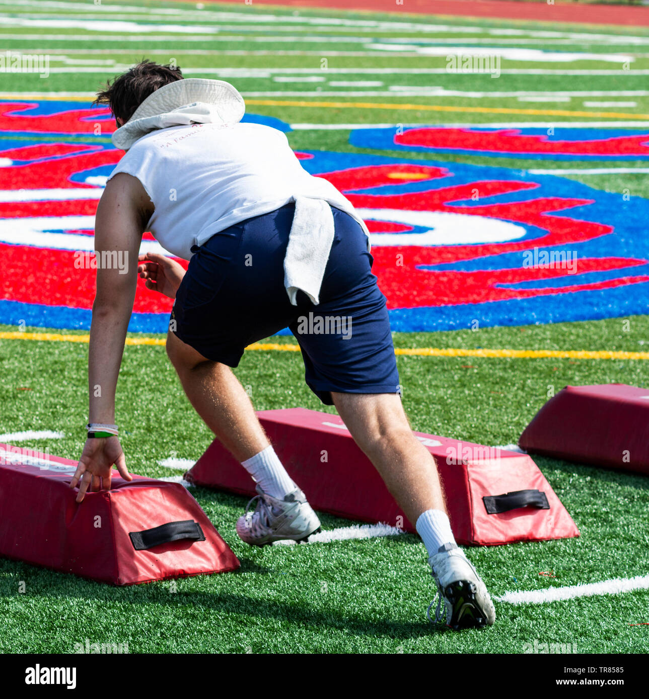 A high school football player is sprinting between barriers suring a