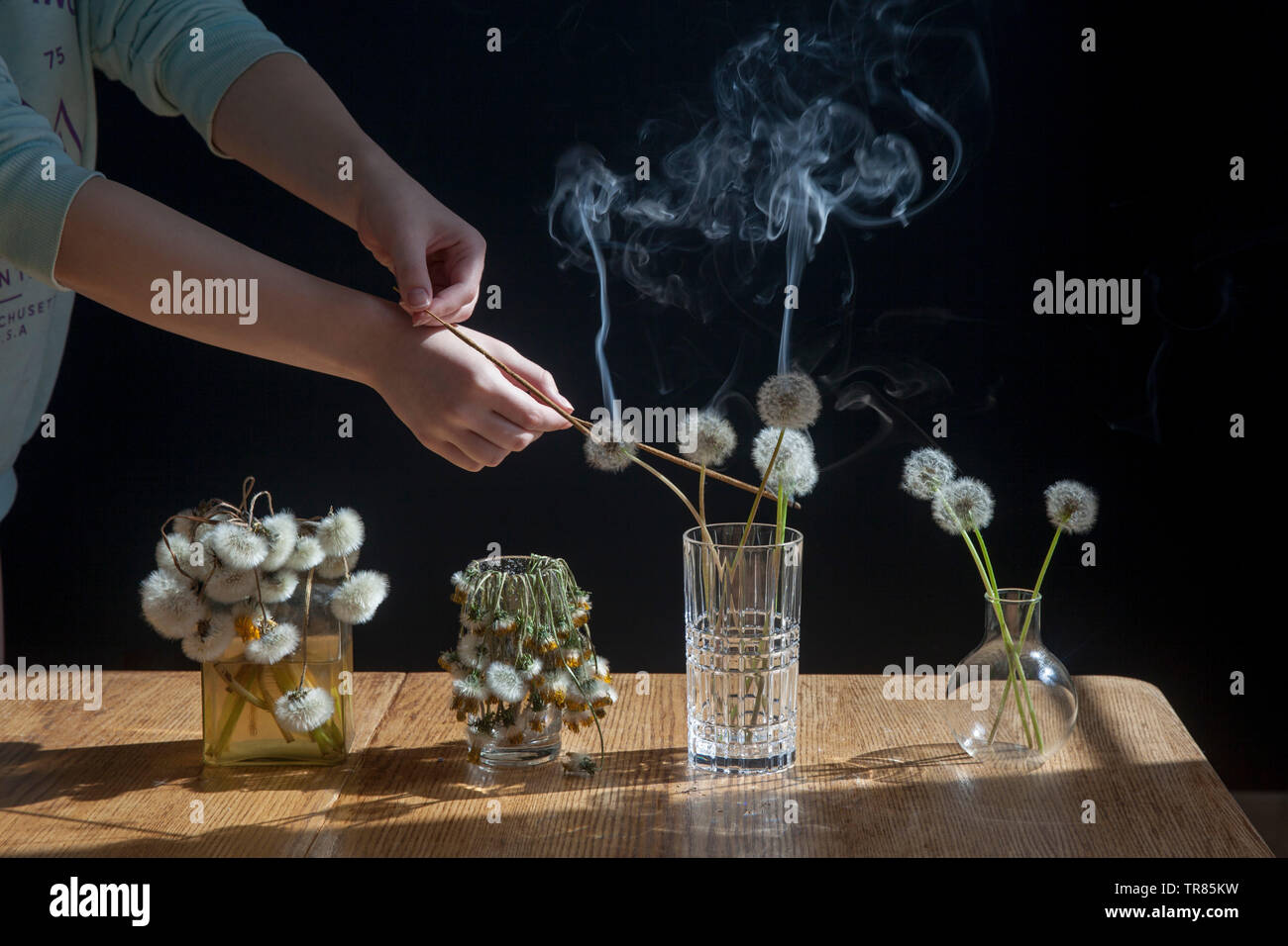 A bouquet of dandelions in a transparent glass on the wooden table ...