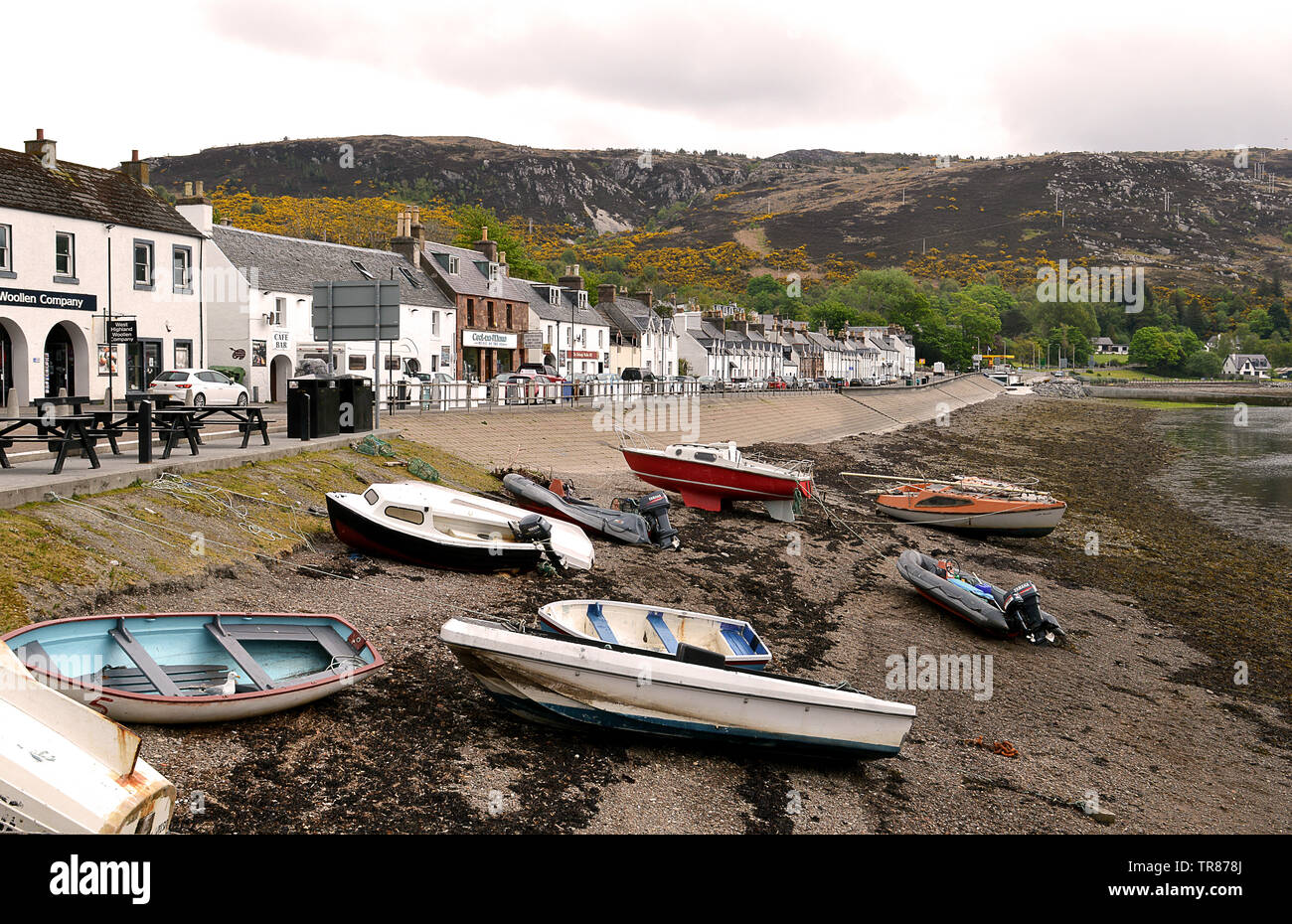 Dinghies pulled up on the beach at the edge of Loch Broom with Shore Street behind in the West Highland village of Ullapool. Stock Photo