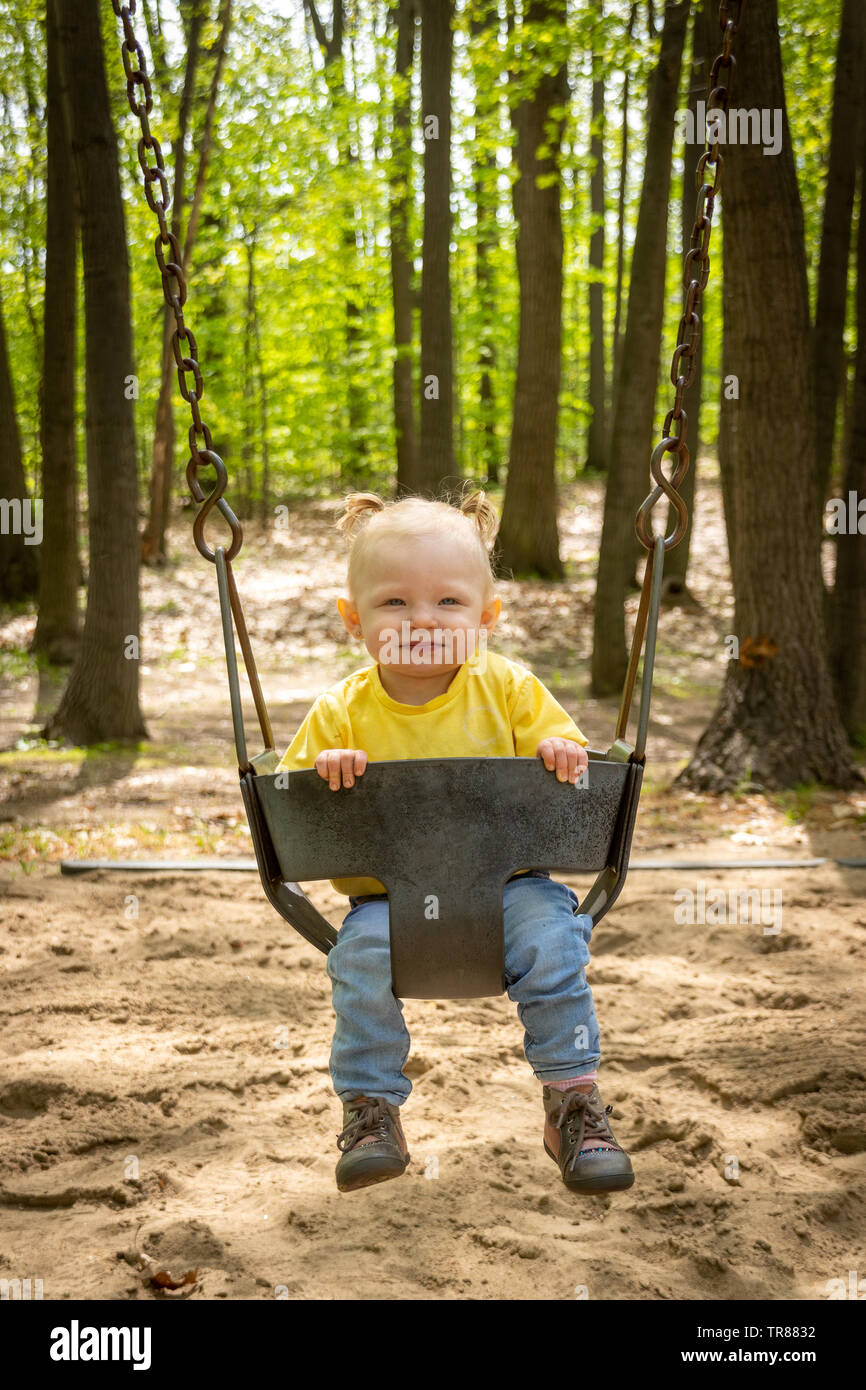 adorable blond caucasian toddler in the swing at the playground Sorel-Tracy Stock Photo