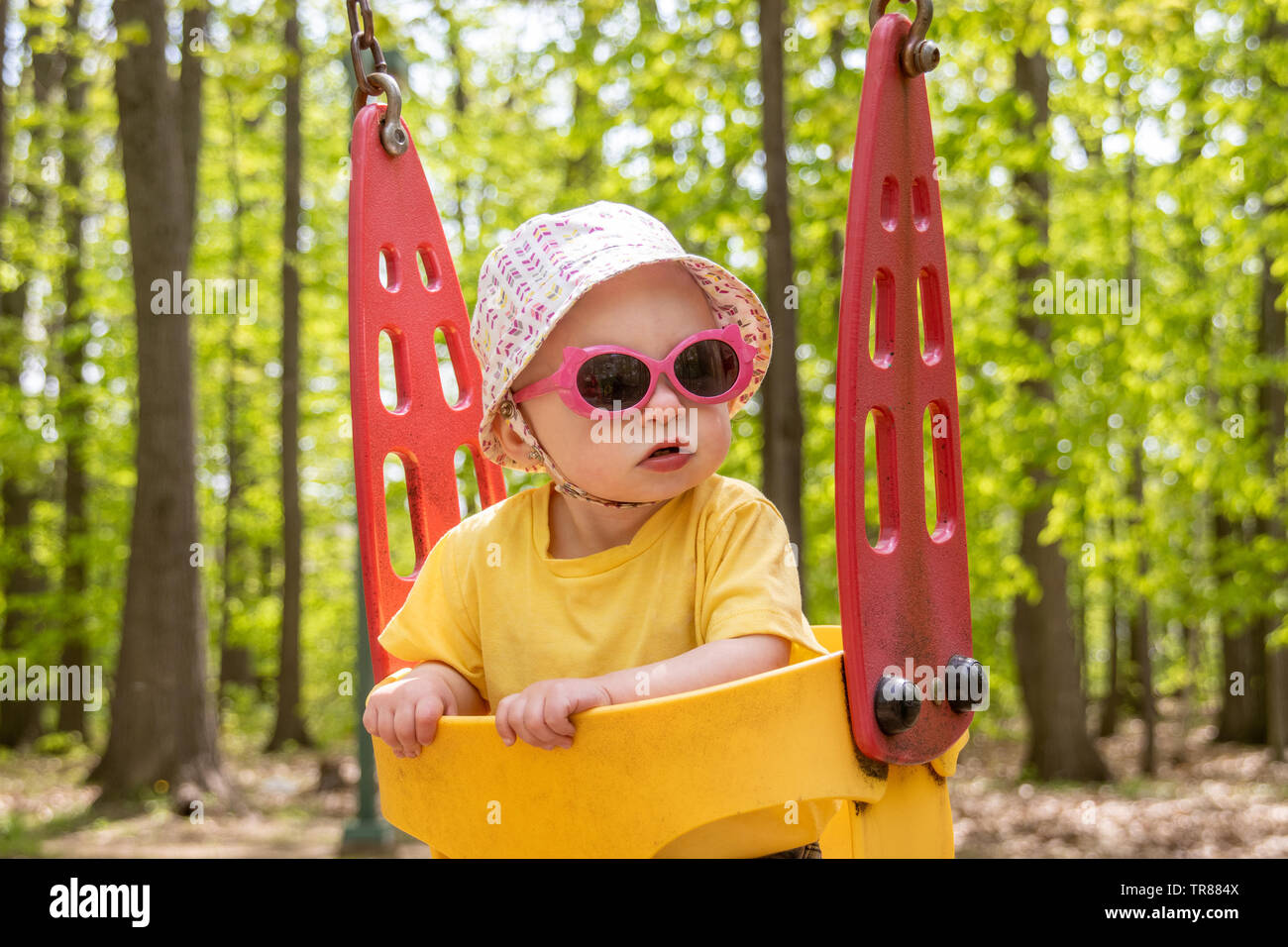 adorable blond caucasian toddler in the swing at the playground Sorel-Tracy Stock Photo