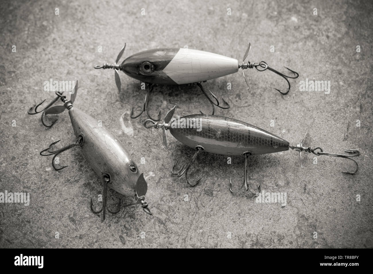 Three old South Bend fishing lures photographed on a stone background. Lures such as these are often called plugs these being equipped with three larg Stock Photo