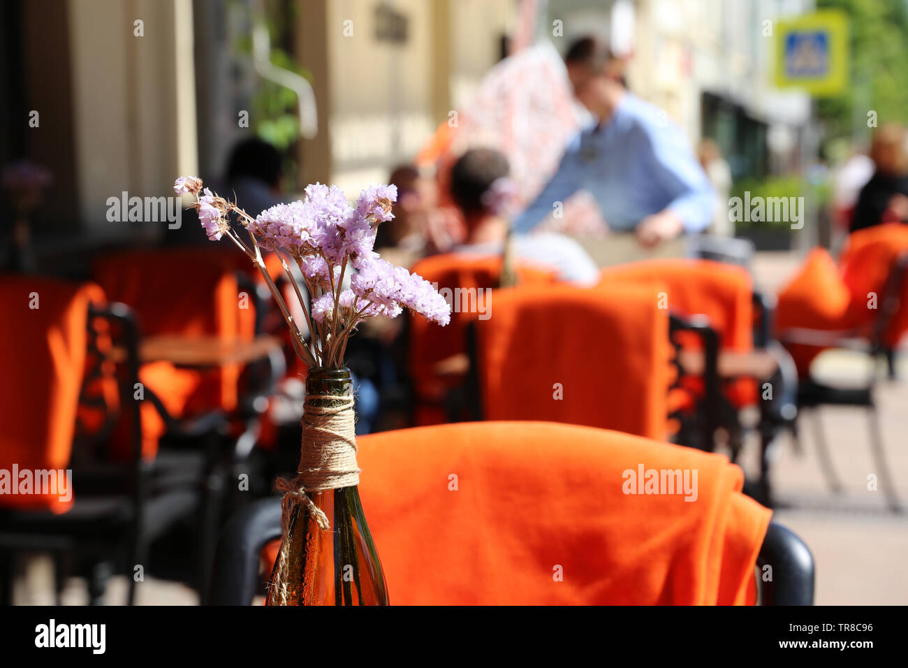 People in street cafe, tables in a restaurant outdoor. Romantic dinner in summer city, visitors and waiter, elegant setting for celebration and date Stock Photo