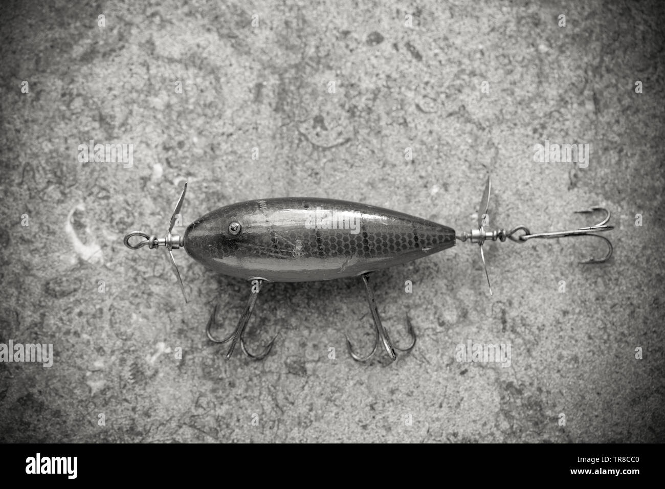 An old South Bend fishing lure photographed on a stone background. Lures such as these are often called plugs this one being equipped with three large Stock Photo