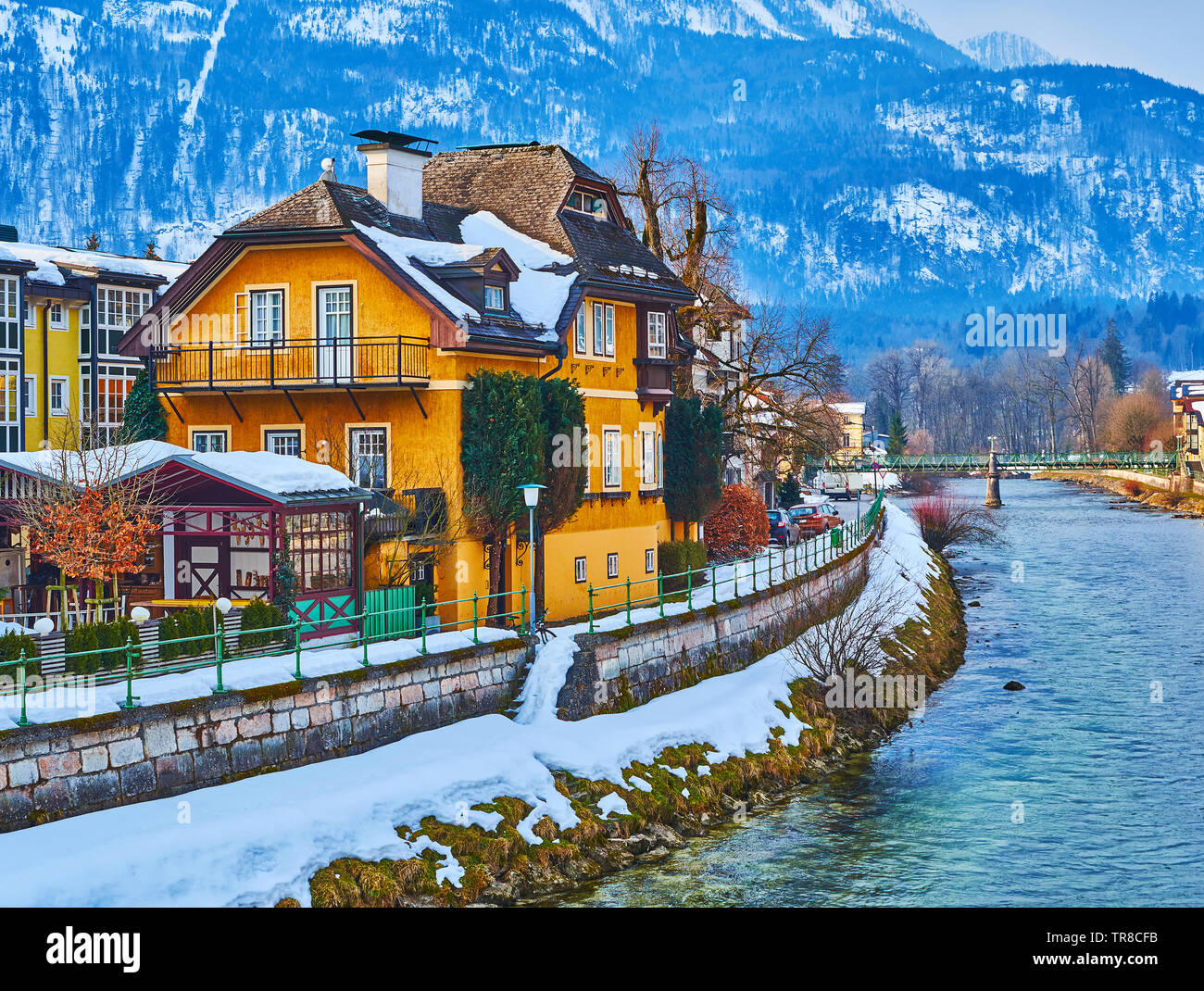 The old villa on the snowbound  bank of Traun river with a slope of Mount Katrin on background, Bad Ischl, Salzkammergut, Austria. Stock Photo