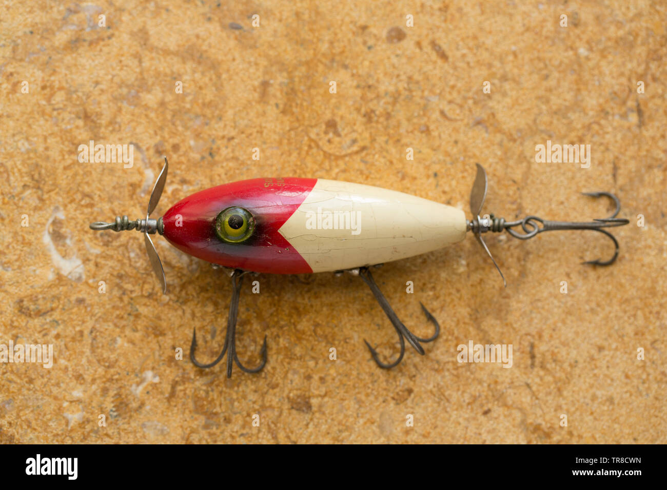 An old South Bend fishing lure photographed on a stone background. Lures such as these are often called plugs this one being equipped with three large Stock Photo