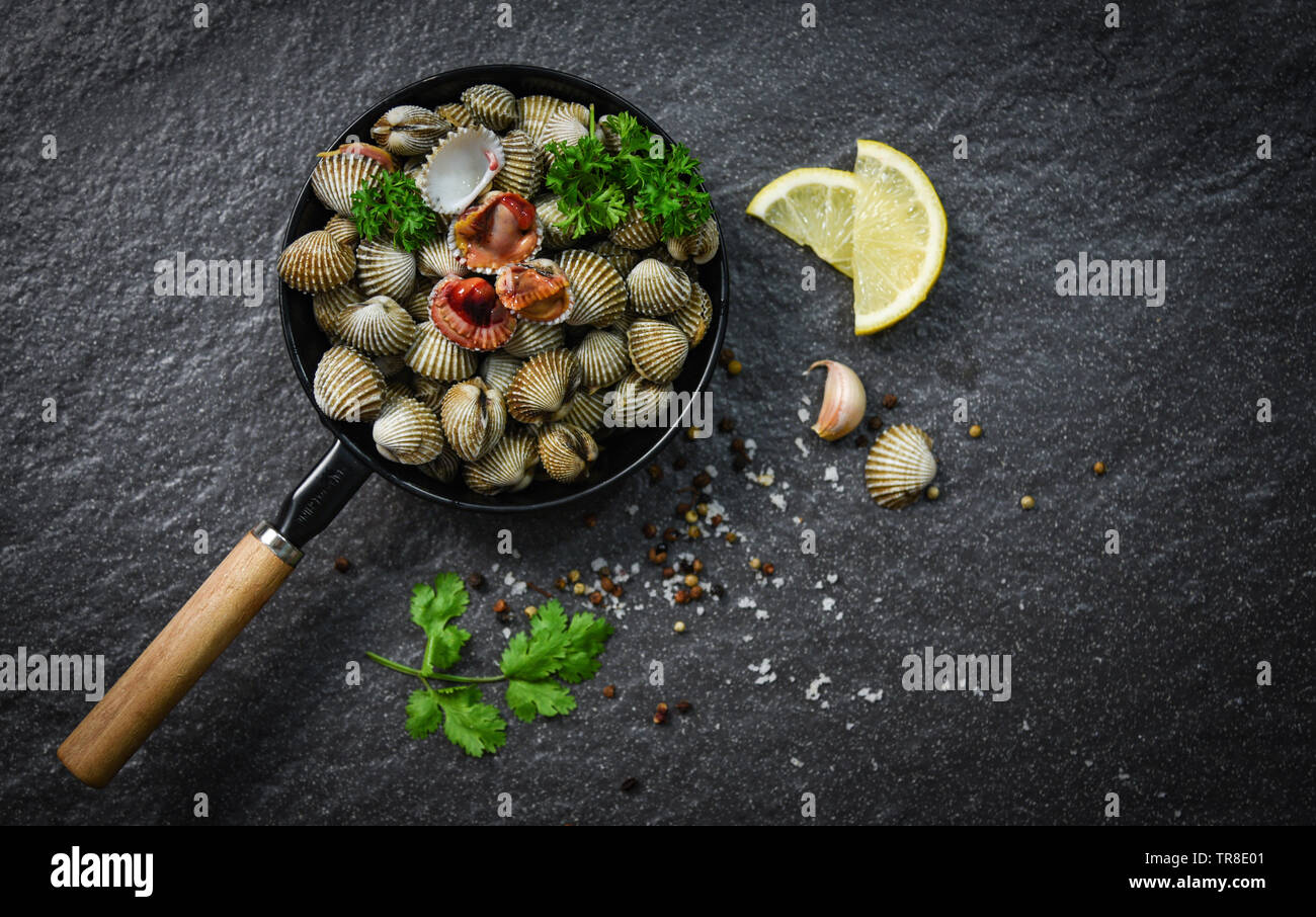 Cockles shellfish seafood plate with herbs and spices on dark