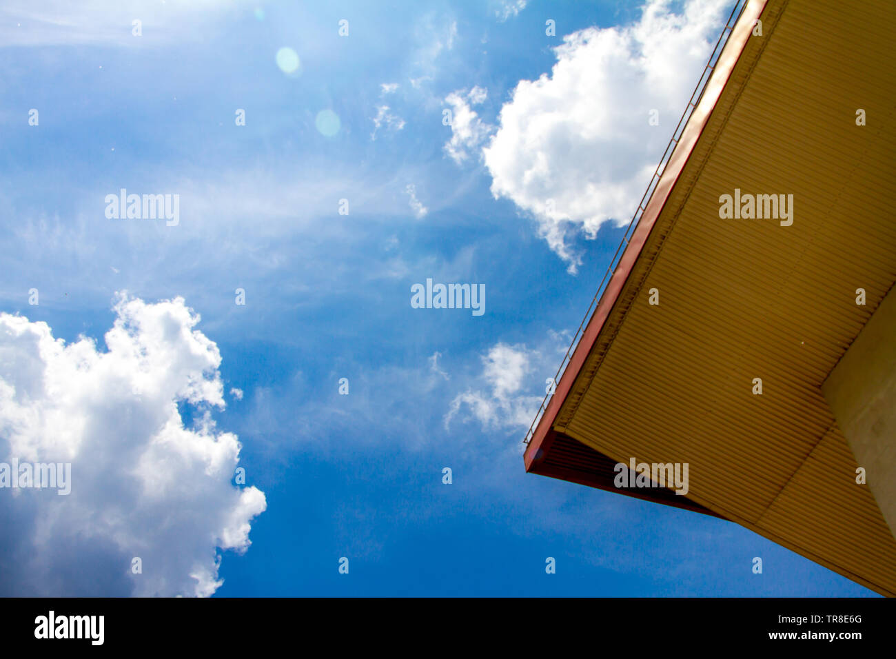 Bottom view of the edge of the roof of the building against the blue sky and clouds, free space for text Stock Photo