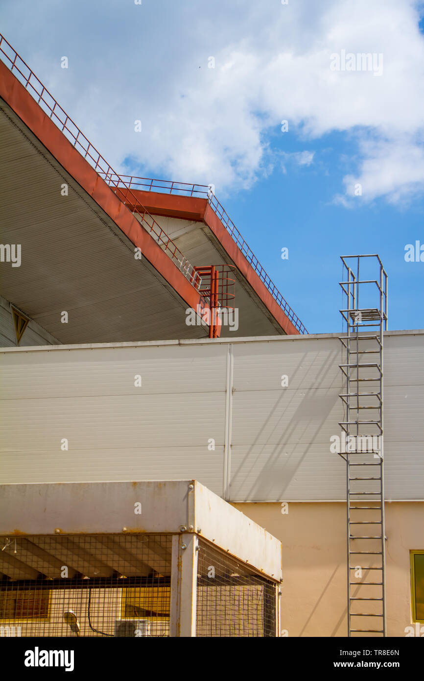 Bottom view of the roof of the industrial pavilion, fence and stairs over the blue sky and clouds, free space for text Stock Photo