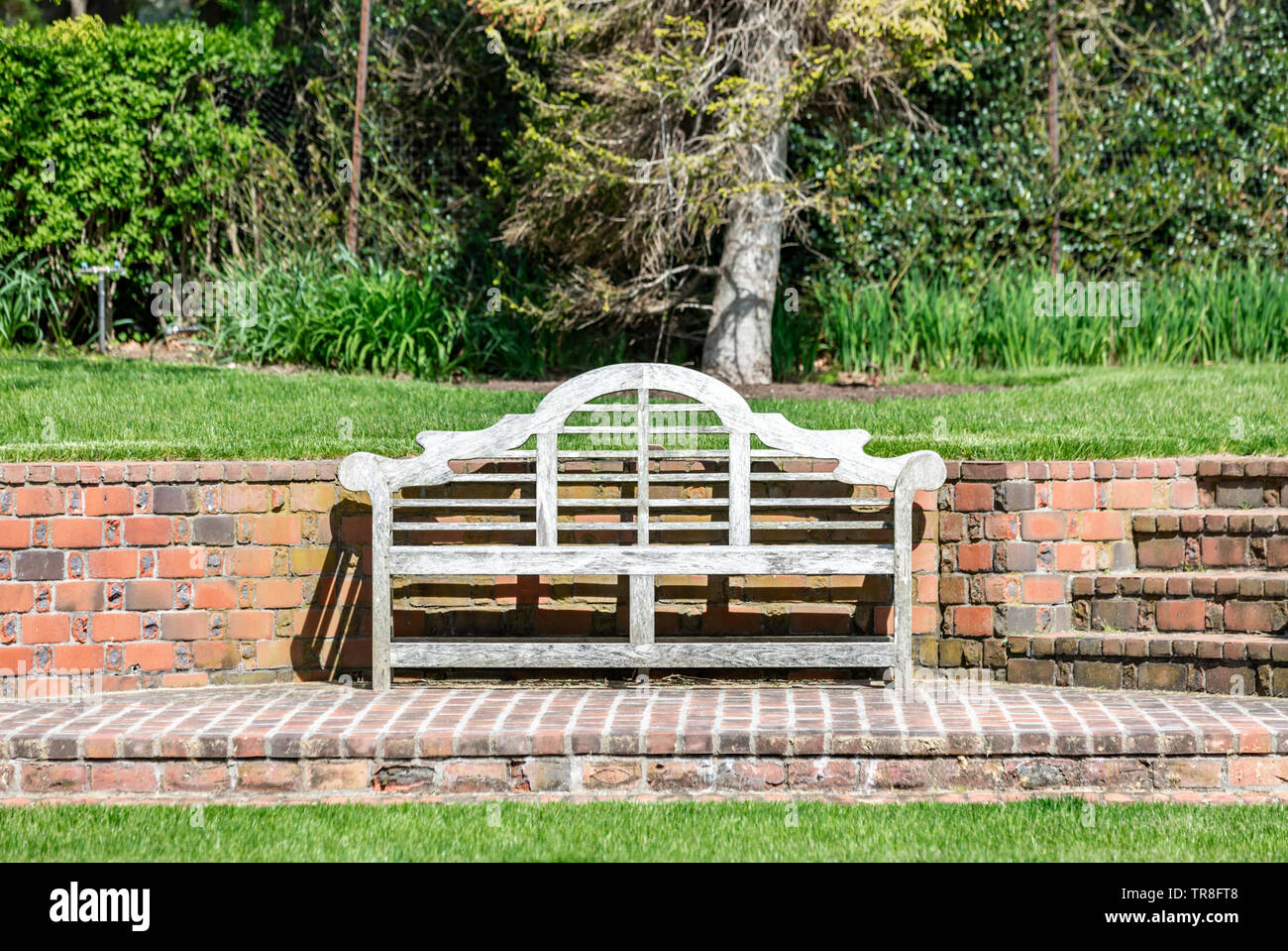 wooden bench on a brick patio with a brick wall in the background Stock Photo Alamy
