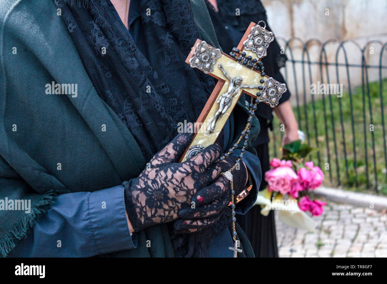 Widow hands holding a religious cross and a rosary Stock Photo