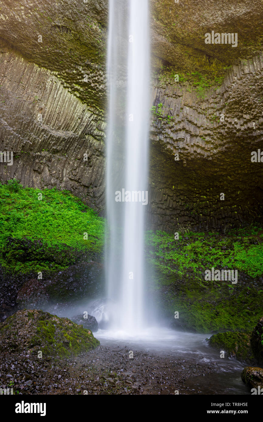 A beautiful waterfall splashes into a pool at the bottom of a natural