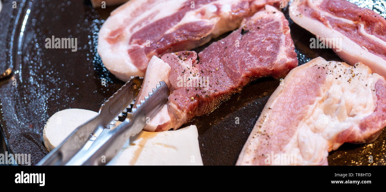 Pan-fried black pork meal in Korea restaurant, fresh delicious korean food cuisine on iron plate with lettuce, close up, copy space, lifestyle Stock Photo