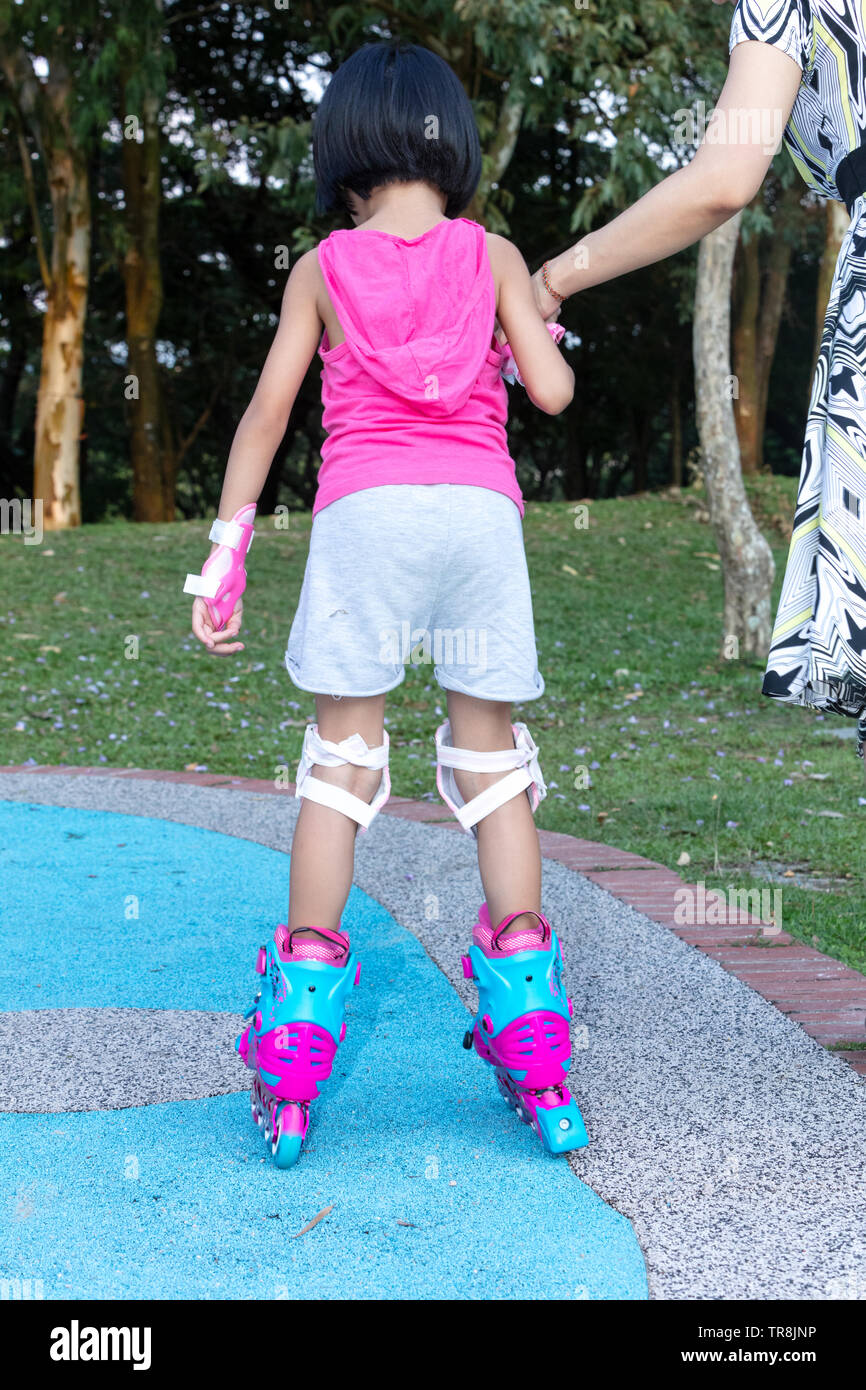 Asian Chinese little girl playing with roller skates at outdoor
