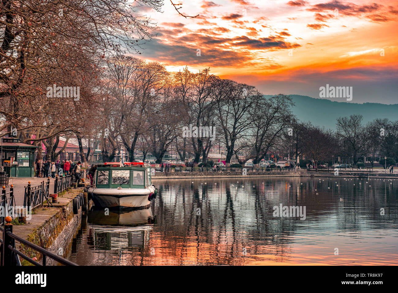 Sunset on lake Pamvotis. Docked boat ready to transfer people to the small island. Greece. Stock Photo