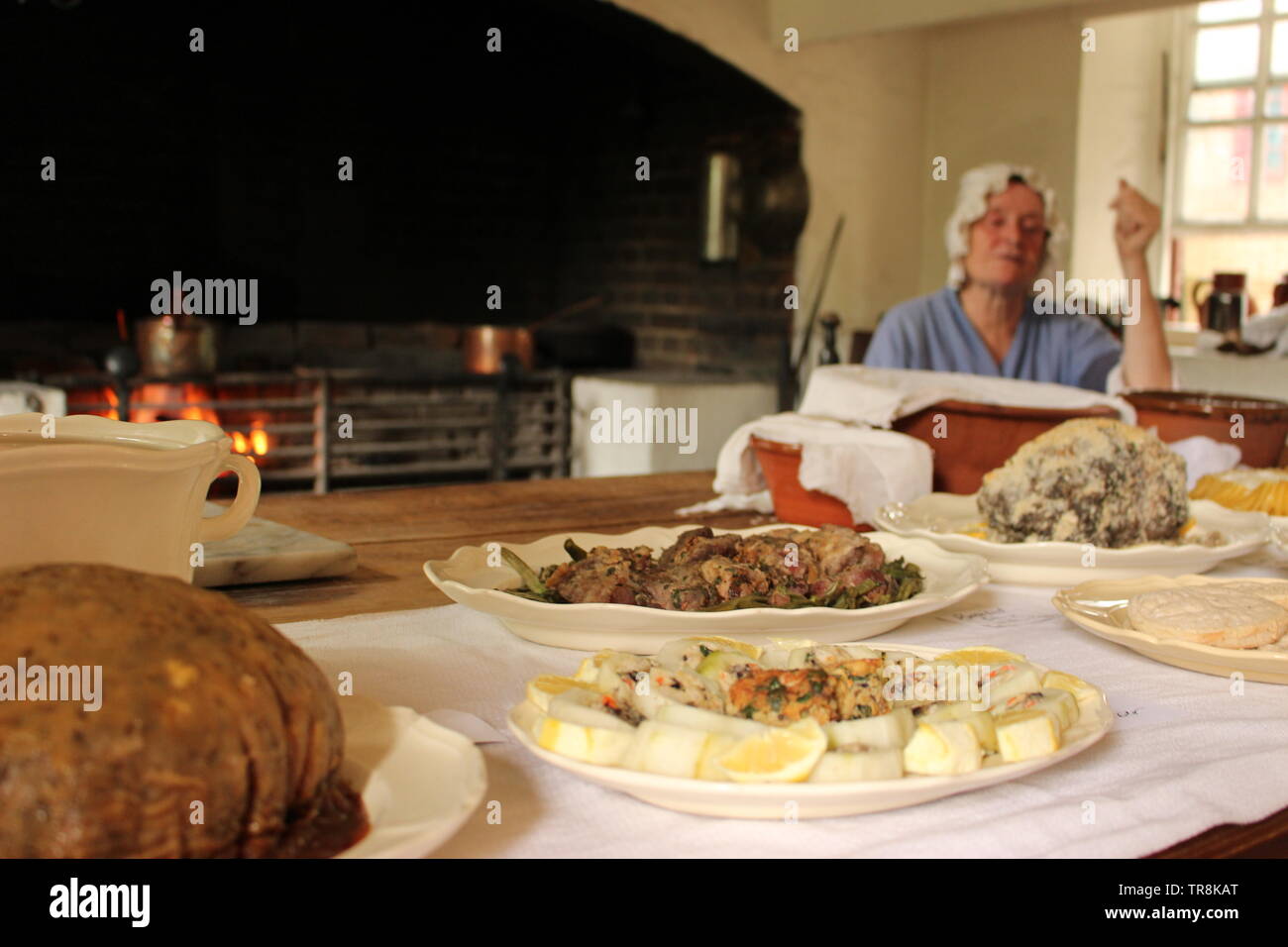 Williamsburg, VA Governor’s Palace kitchen showing an example meal that could’ve been served at the Palace in the 1780s.  Character actor in the backg Stock Photo