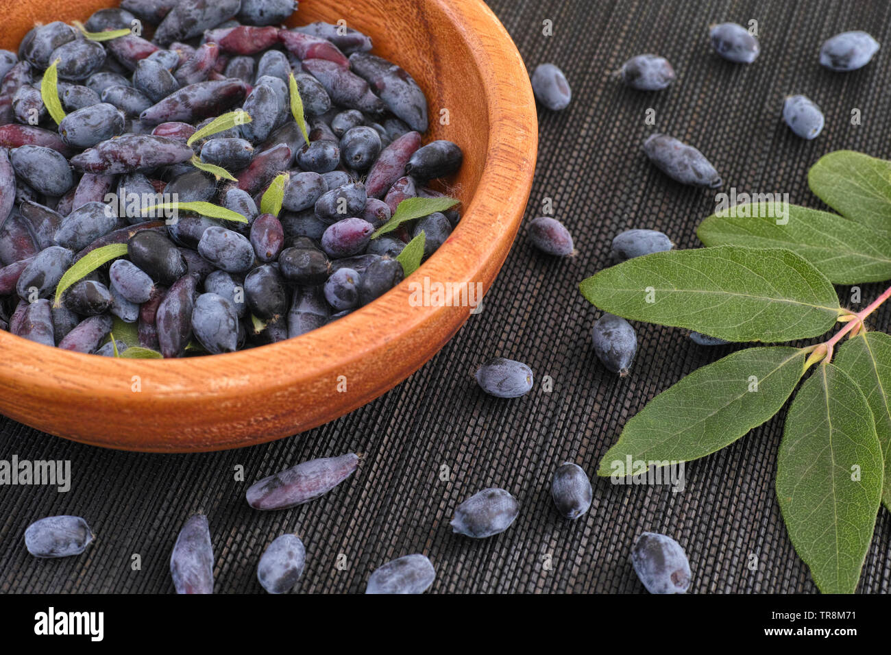Blue fly honeysuckle in a wooden bowl. Close up. Stock Photo