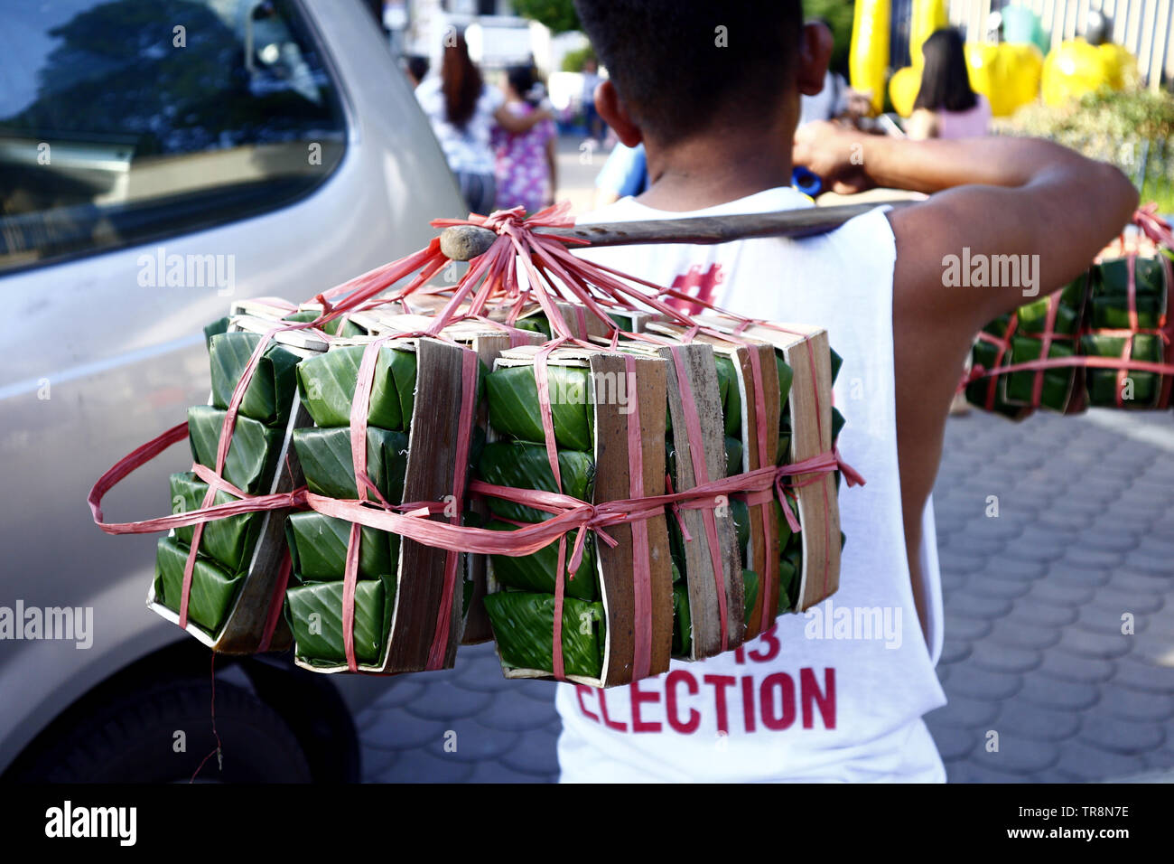 ANTIPOLO CITY, PHILIPPINES – MAY 30, 2019: A street vendor peddles Kesong Puti or cheese made from carabao milk wrapped in banana leaves at a public p Stock Photo