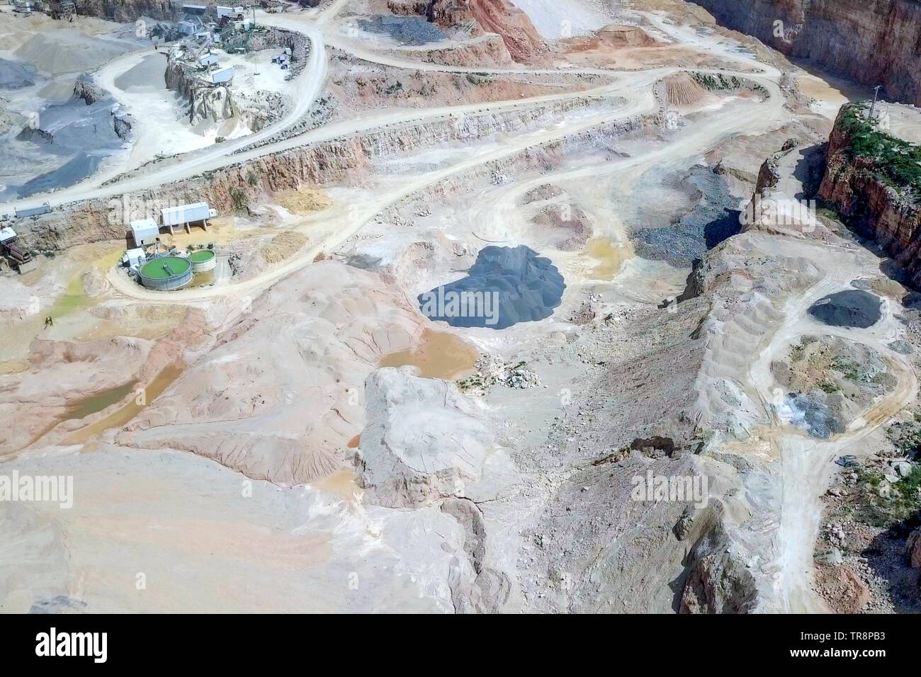 Large Quarry during work hours with Stone sorting conveyor belts - Aerial tour. Stock Photo