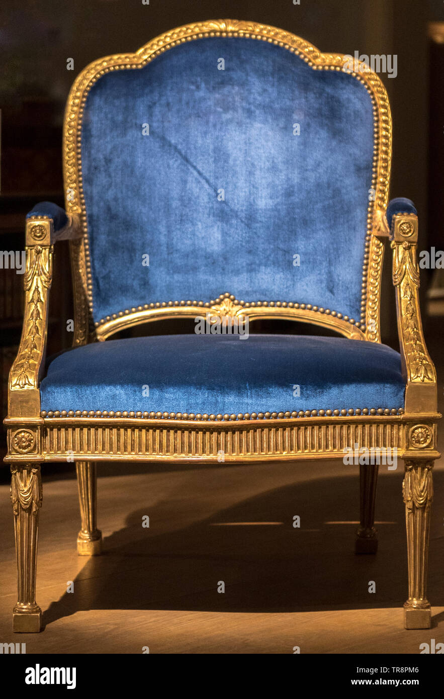 Large Blue Fabric Throne Chair with Gold Frame in Spotlight Stock Photo