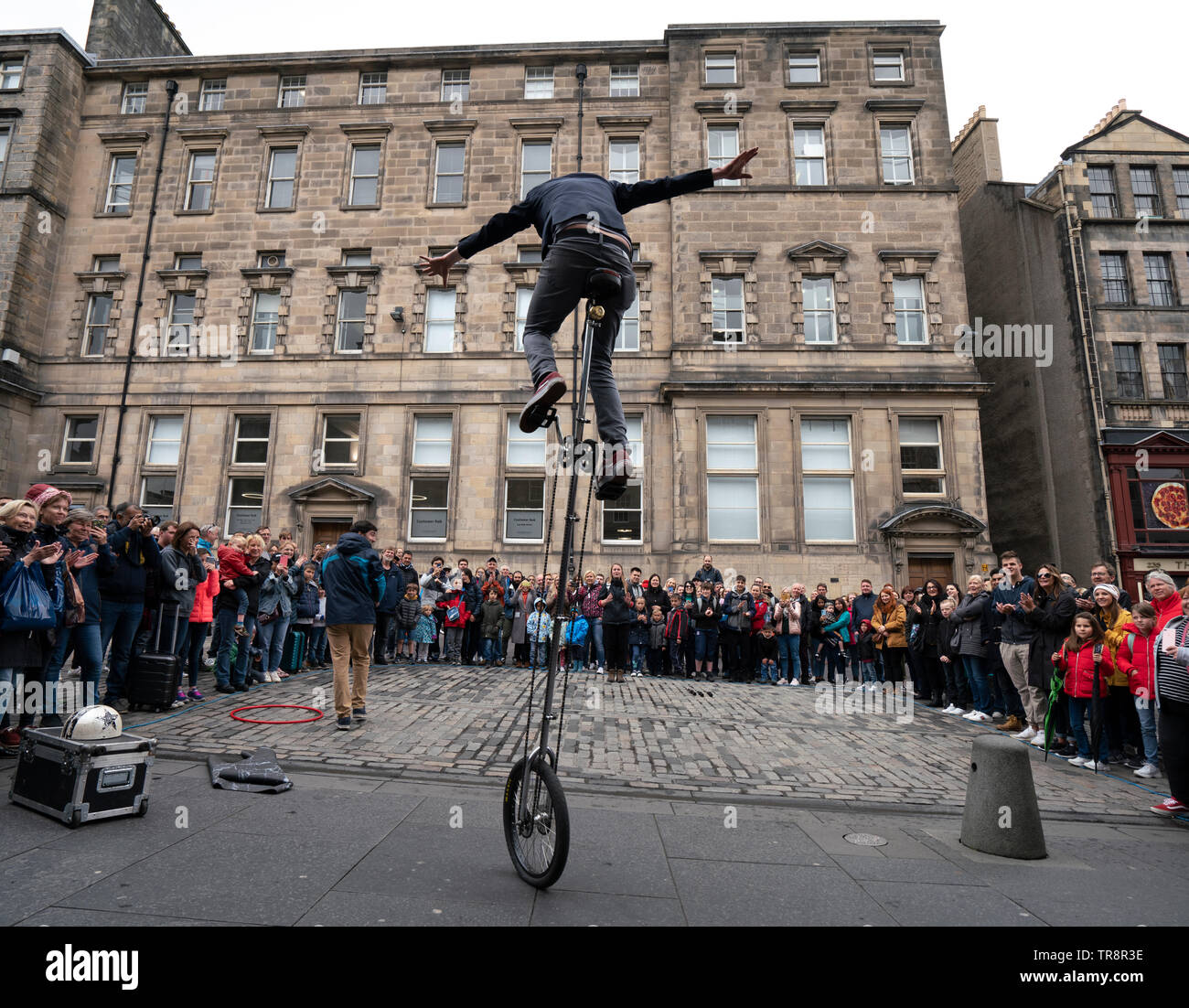 Street performer on unicycle performs to crowd on the High Street Royal Mile in Edinburgh Old Town, Scotland, UK Stock Photo