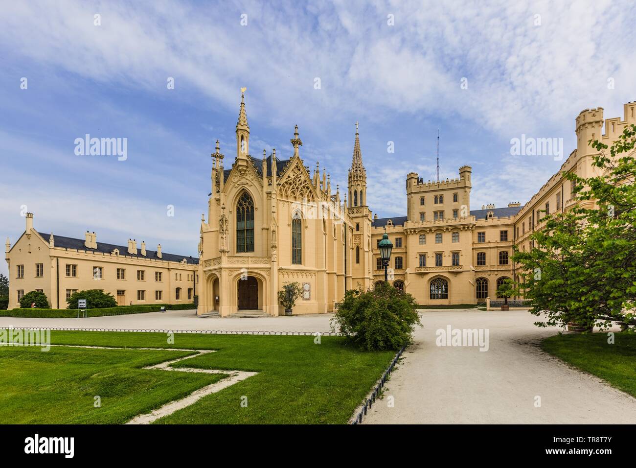 Lednice, Czech Republic - May 27 2019: Famous Lednice castle in South Moravia with yellow facade. Green lawn, trees and sand footpath in foreground. Stock Photo