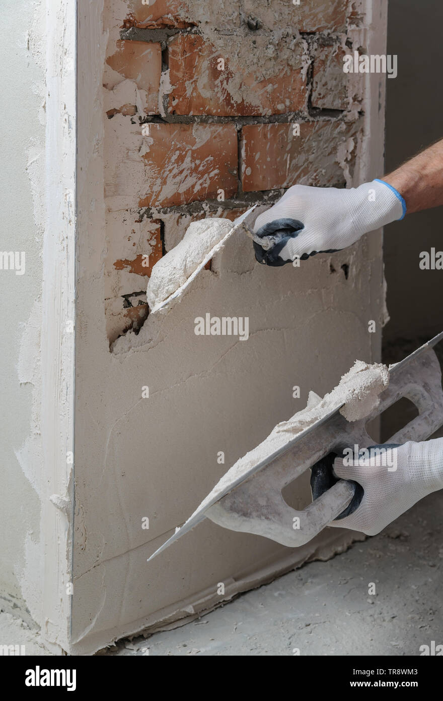 Worker's hands are using trowels for gypsum plaster. Stock Photo