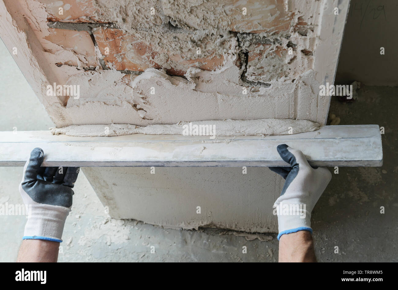 Worker is putting a gypsum plaster on a brick wall. Stock Photo