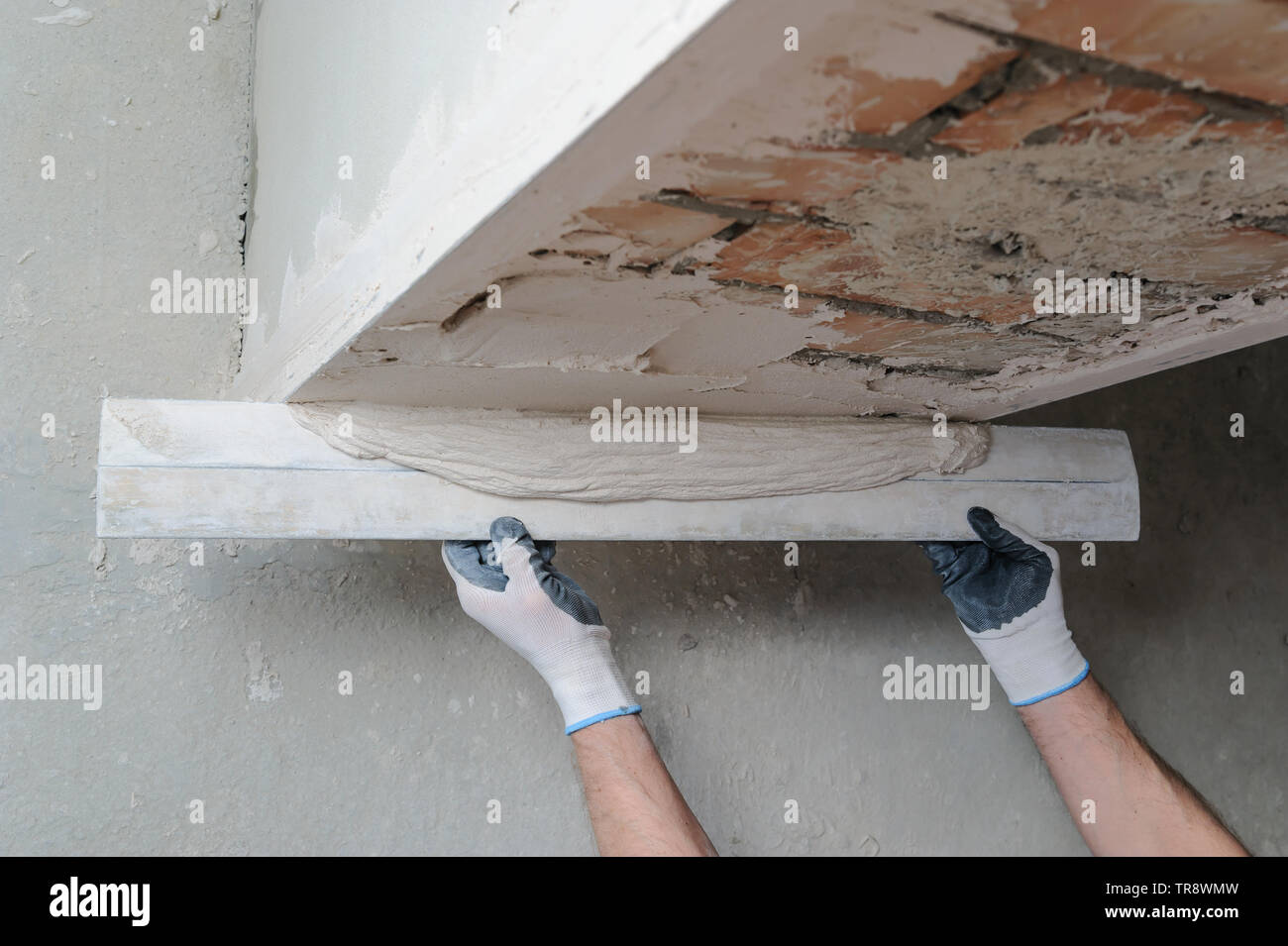 Worker's hands are using a ruler for gypsum plaster Stock Photo - Alamy