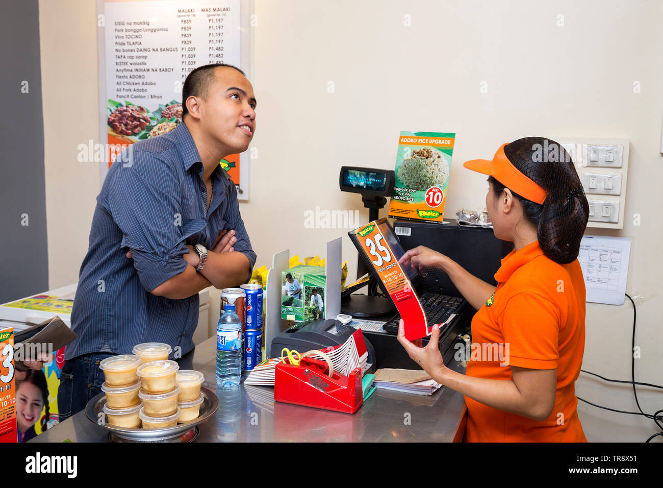 Manila, Philippines - July 26, 2016: A customer ordering food at the cashier in a filipino reastaurant Stock Photo