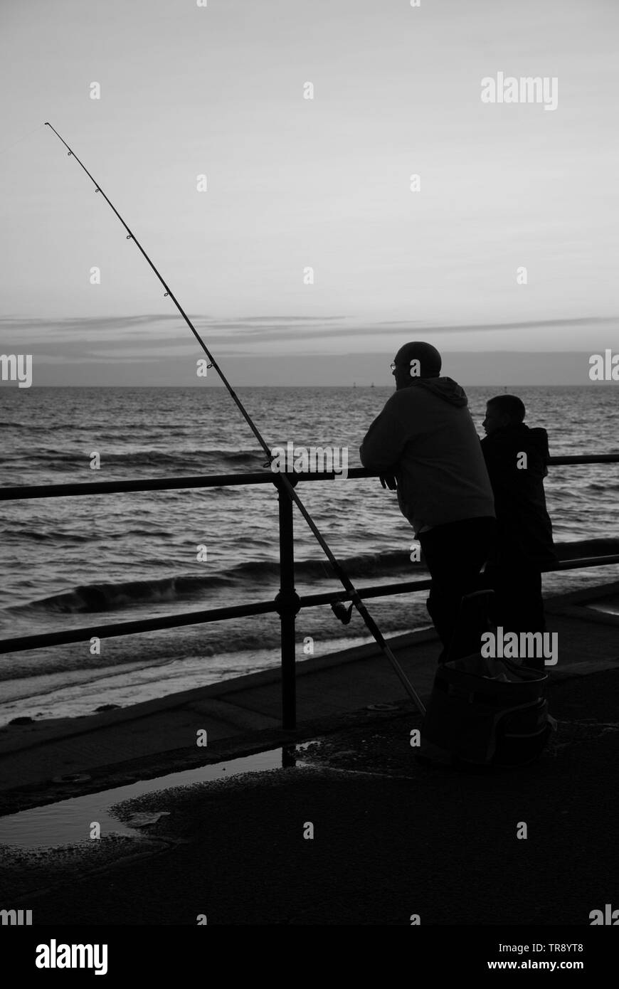 Grandfather & Grandson fishing off the sea wall at Crosby beach Liverpool. Stock Photo
