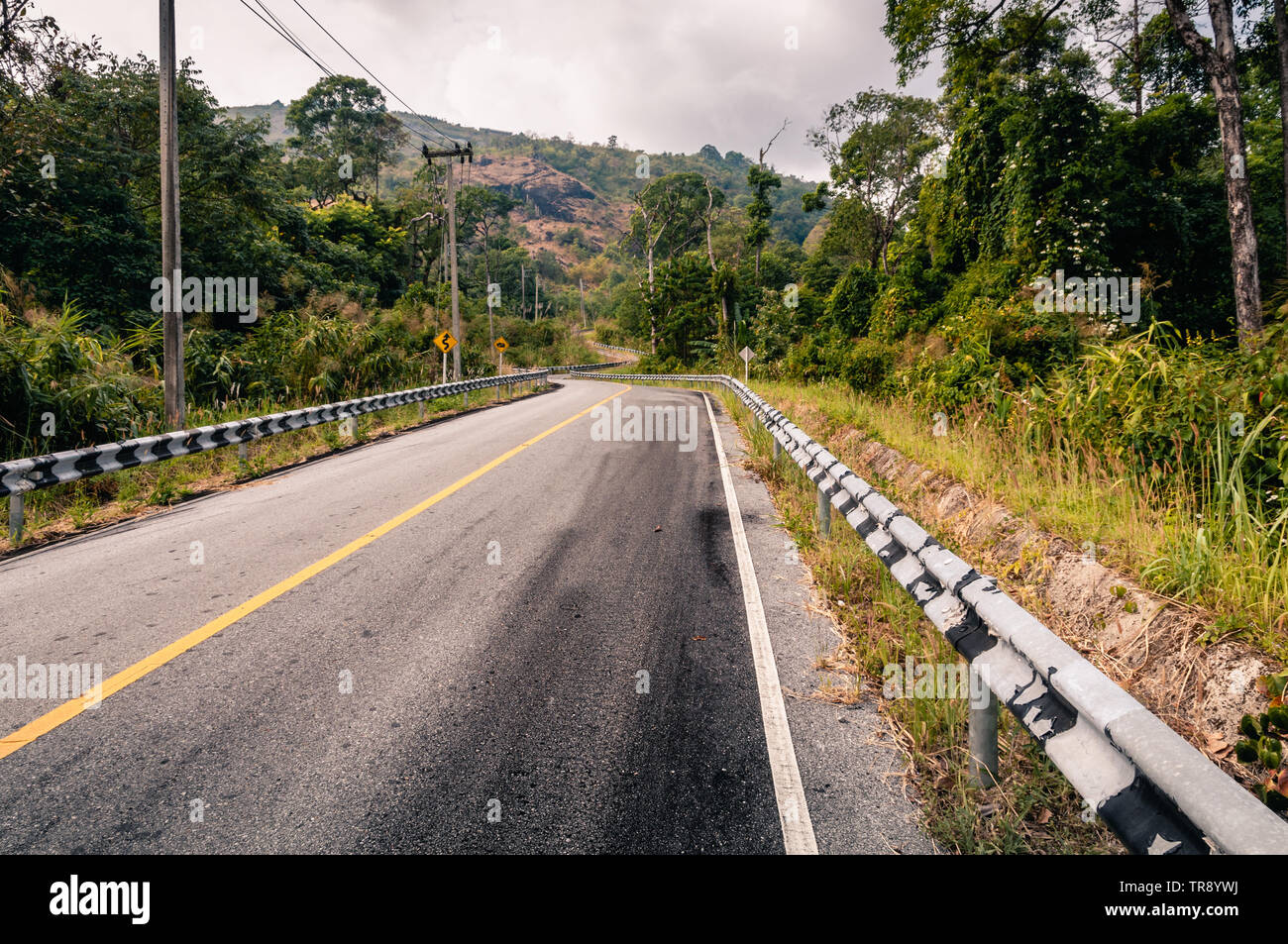 Winding mountain asphalt road through the forest in Khao Laem National park in Kanchanaburi Province of Thailand. Stock Photo