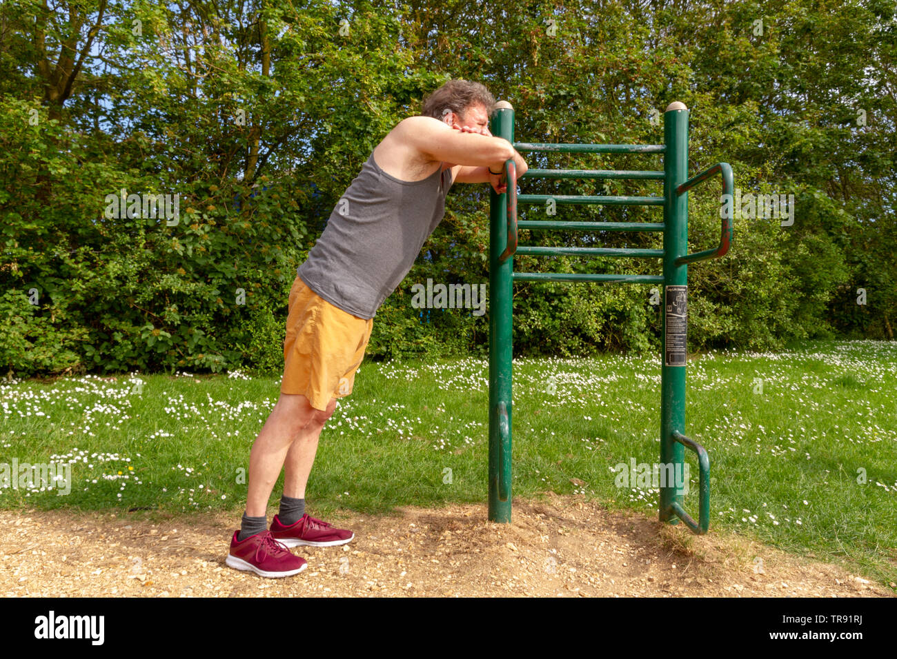 Older man taking a rest in between exercising in the outdoor gym. Healthy outdoors lifestyle concept. Stock Photo