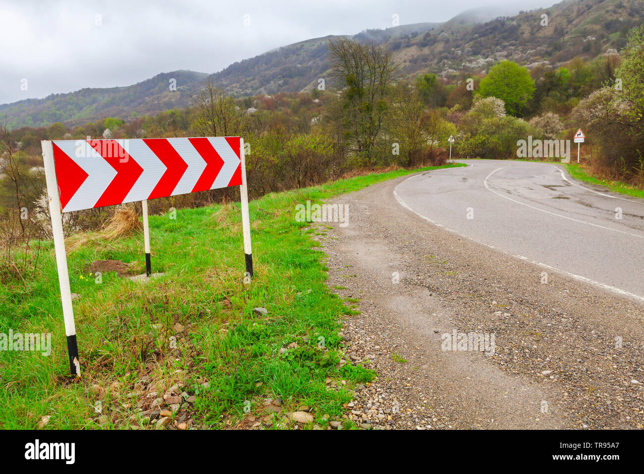 Dangerous Turn Red And White Striped Arrow Road Sign Mounted On A Roadside Of A Mountain Road Stock Photo Alamy