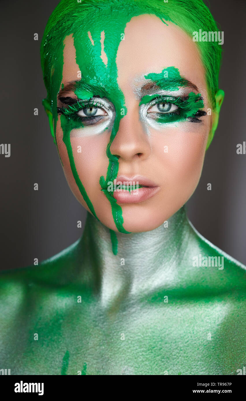 High fashion model. An amazing woman with green metallic makeup and leaking green neon paint. Glitter vivid makeup Stock Photo