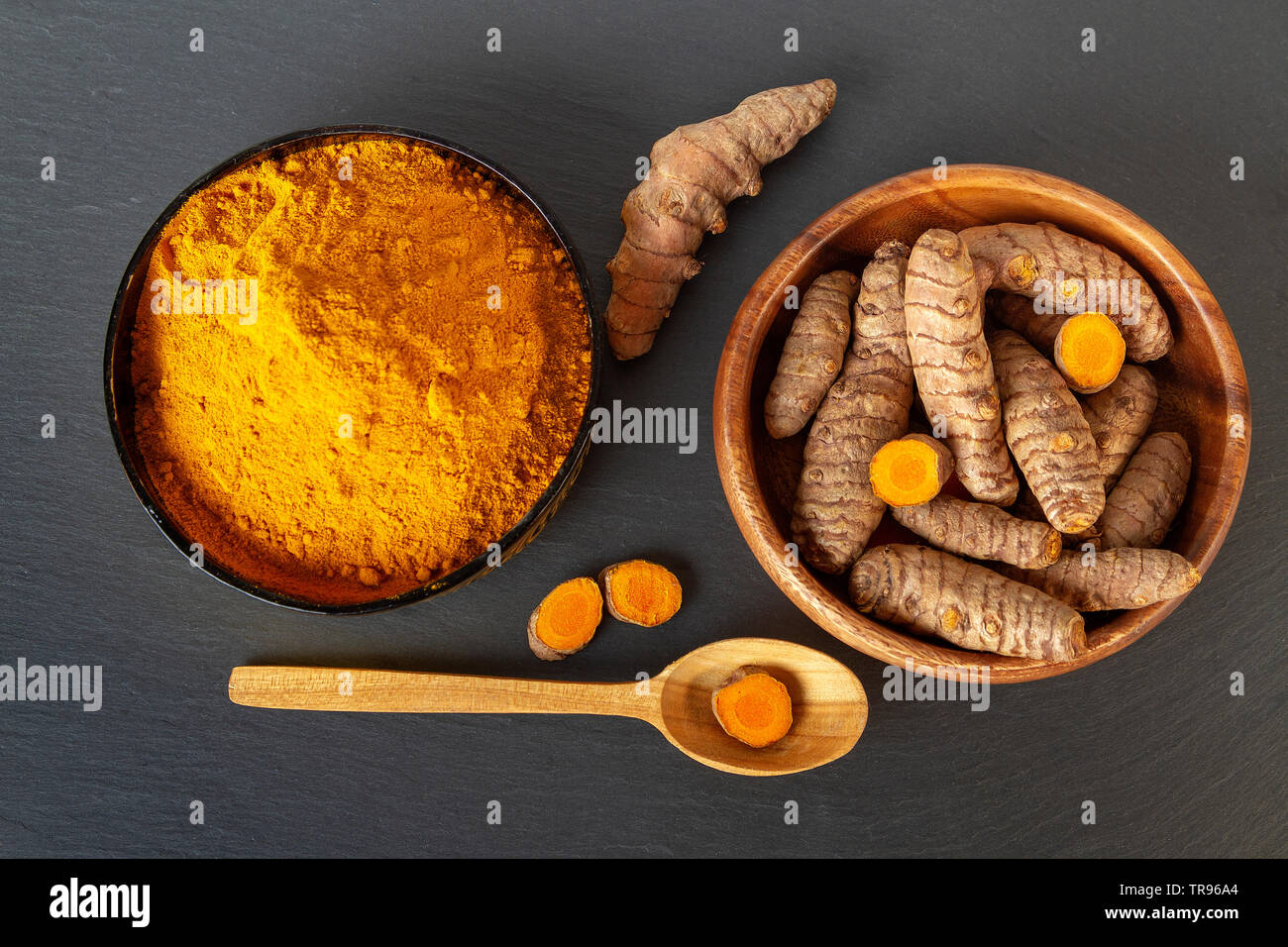 Turmeric roots and powder on gray slate background, overhead shot Stock