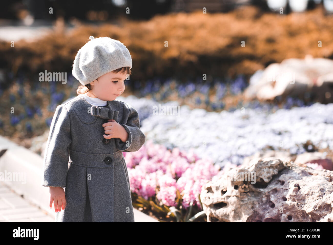Stylish baby girl walking in park wearing  trendy jacket. Autumn season. Childhood. Stock Photo