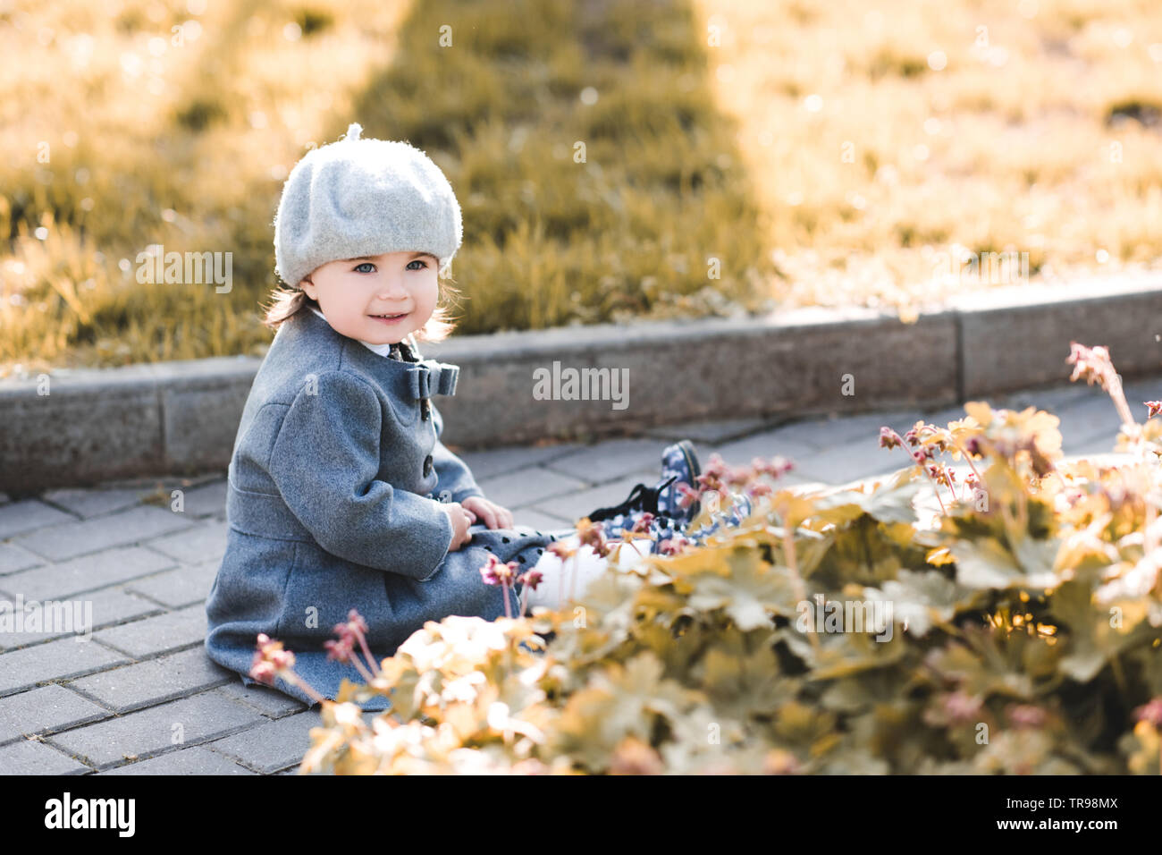 Cute baby girl wearing stylish winter jacket in park. Childhood. Stock Photo