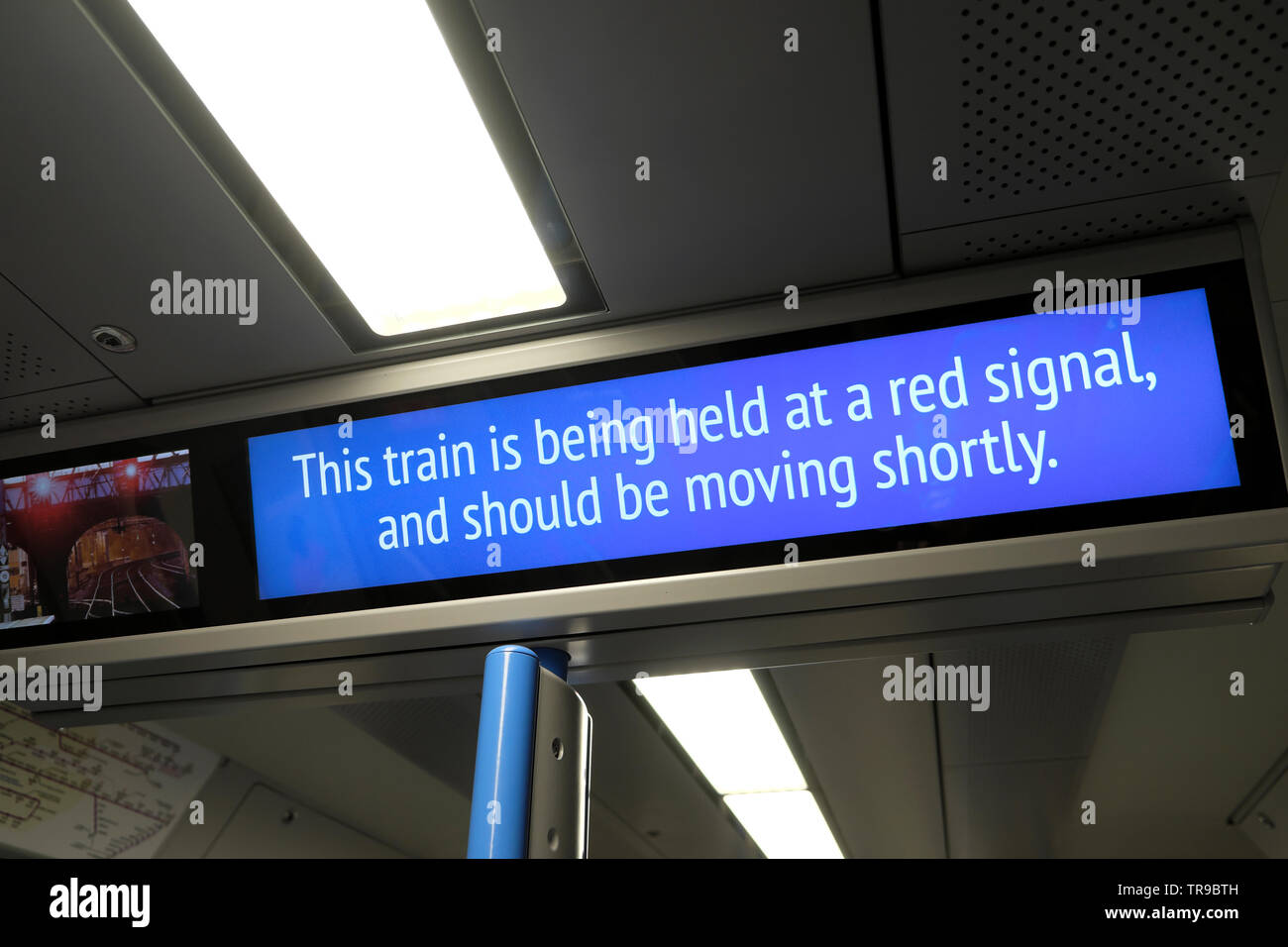 'This train is being held at a red signal, and should be moving shortly' sign on a train carriage due to disruption of service in London England UK Stock Photo