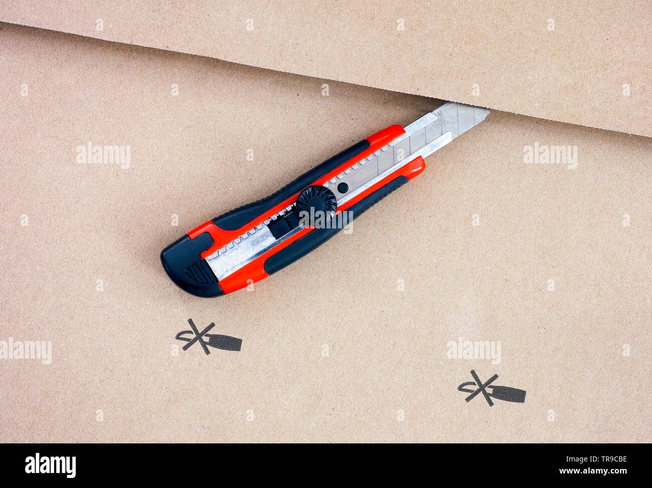 Paper knife on cardboard with Do not open with a knife sign. Closeup