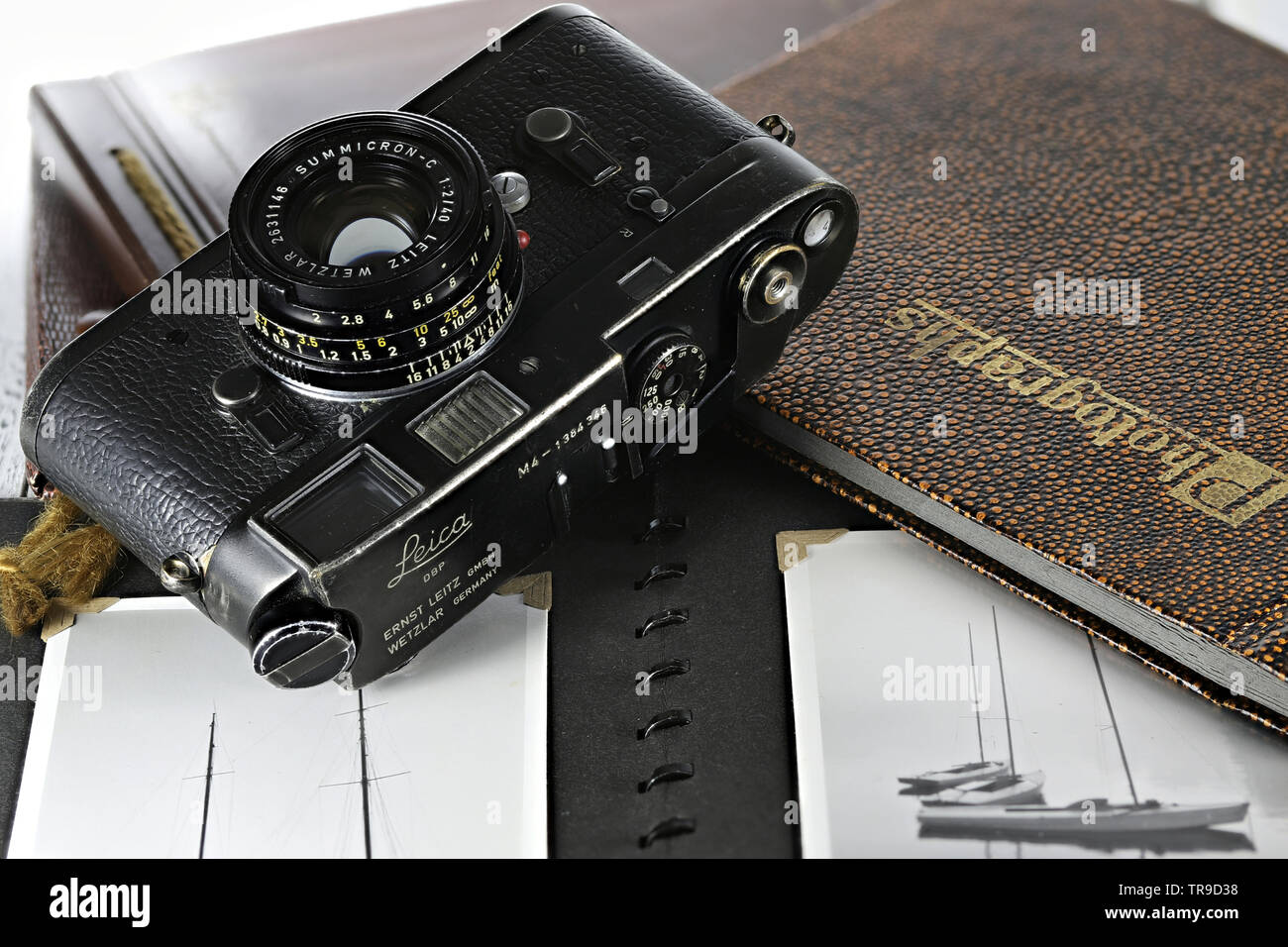Heavy used Leica M4 camera with photo album on wooden table. The Leica M4 is a 35 mm rangefinder camera produced by Ernst Leitz GmbH from 1966 - 1975. Stock Photo